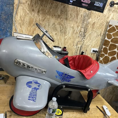 Restored vintage child's pedal plane with red seat